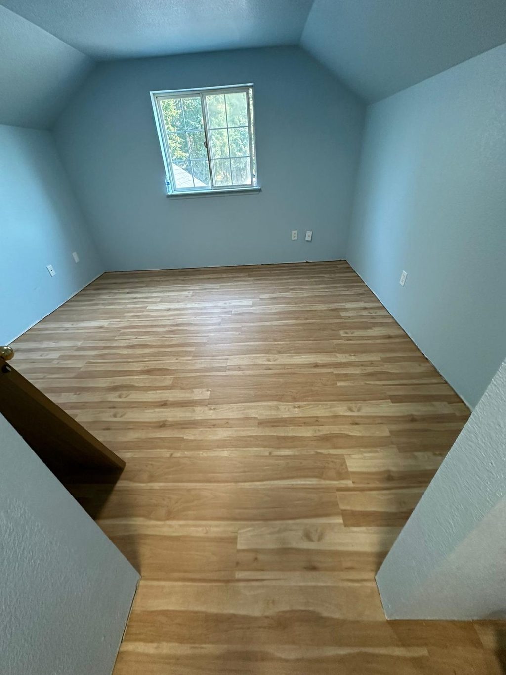Empty bedroom with a newly finished light wood floor and blue walls, an Eco Place flooring project