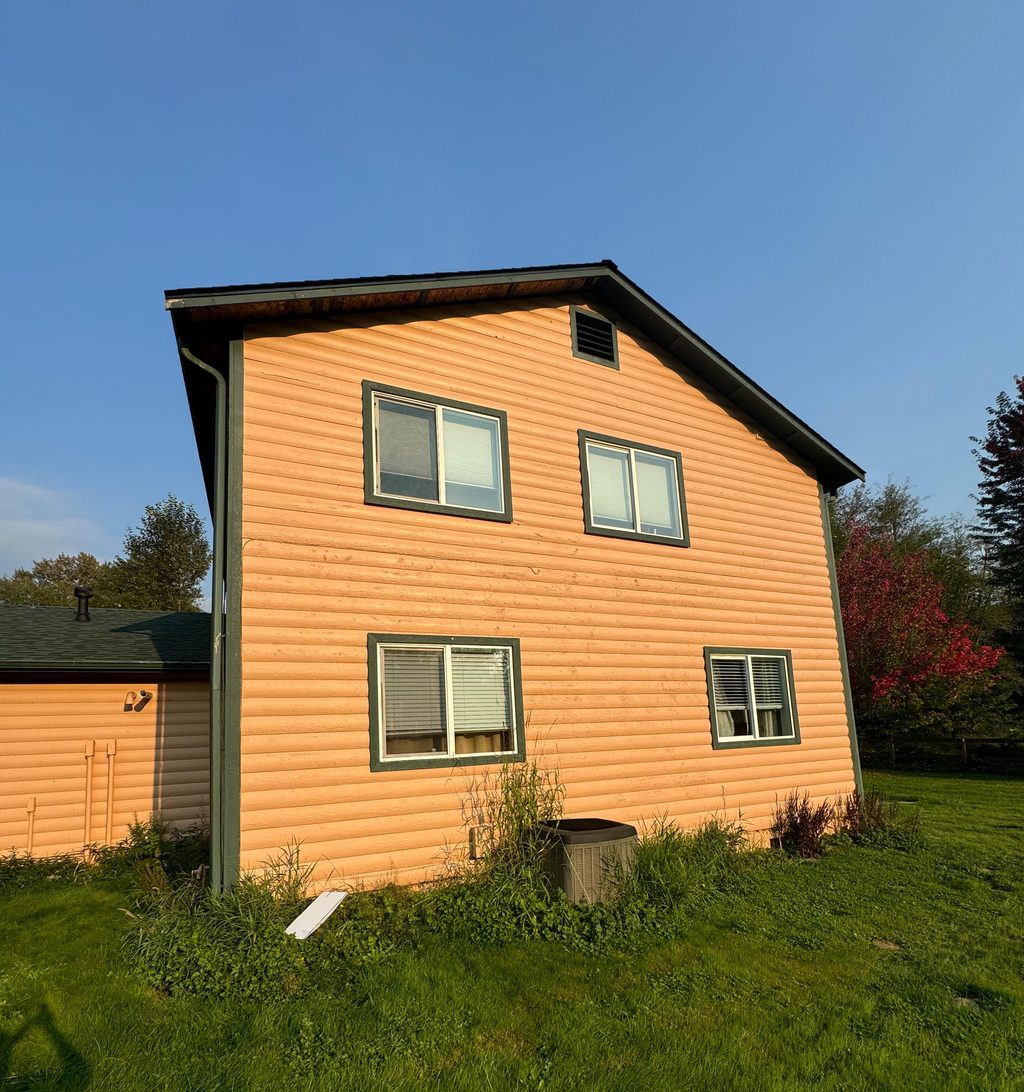 Finished house exterior with new tan siding and green window trim, an Eco Place siding project